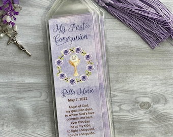 May include: Purple and white bookmark with a gold chalice and the text "My First Communion" and "Bella Marie" with the date "May 7, 2022". The bookmark has a purple tassel.