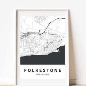Könnte beinhalten: Ein gerahmter Schwarz-Weiß-Karten-Druck von Folkestone, mit dem Namen der Stadt und den Koordinaten in einer modernen Schriftart. Die Karte zeigt Straßen und Küstenmerkmale.