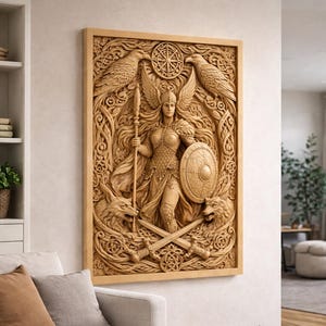 May include: A wooden relief carving depicting a winged figure with a spear and shield, surrounded by wolves and eagles. The artwork is framed in light wood, displaying intricate details and a mythological theme. The carving includes crossed swords and a circular design.