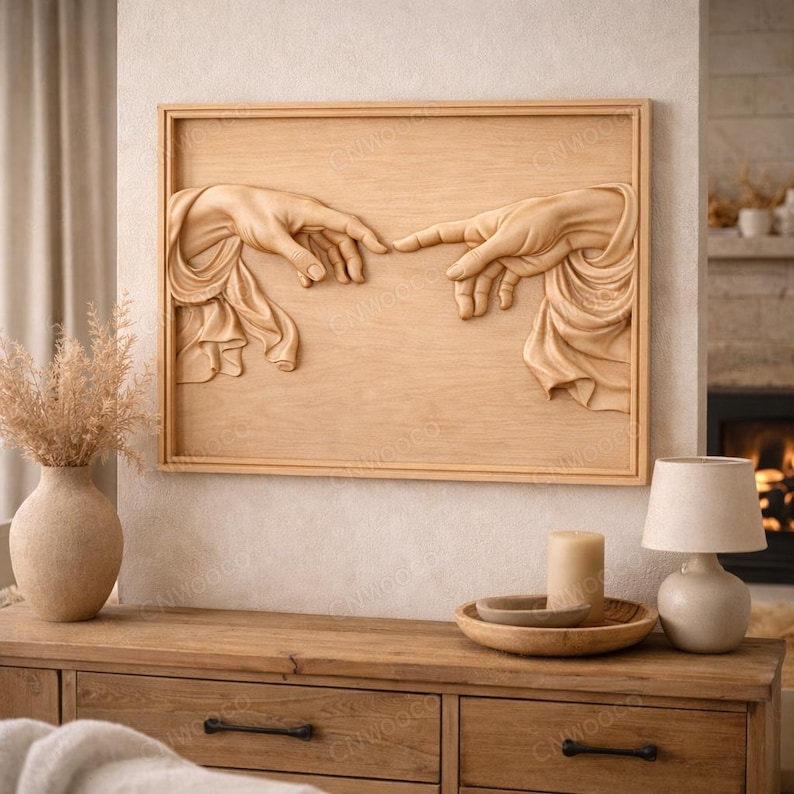 May include: A wooden wall art piece featuring a carved relief of two hands nearly touching, a depiction of the iconic 'Creation of Adam' scene. The artwork is framed in a light brown wood, with the hands and drapery rendered in fine detail.