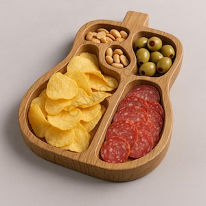 May include: A guitar-shaped wooden serving platter filled with snacks. It holds potato crisps, peanuts, green olives, and sliced salami. The wood has a natural grain and a light brown colour.