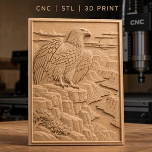 May include: A rectangular wooden relief carving featuring an eagle perched on a cliff edge overlooking a canyon landscape with a river and trees. The top of the piece displays the text CNC | STL | 3D PRINT in a clean, sans-serif font.