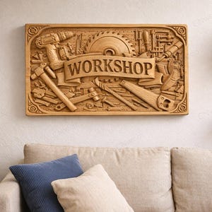 Peut inclure: Panneau rectangulaire en bois avec le mot "WORKSHOP" sculpté au centre, entouré de gravures détaillées d'outils tels qu'une perceuse, une lame de scie, un marteau et une scie. Le panneau est de couleur marron clair.