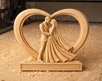 May include: A wooden sculpture of a couple embracing, set within a heart-shaped frame. The figures are carved in detail, with the bride wearing a flowing gown. The sculpture is made of light-colored wood and rests on a rectangular base.
