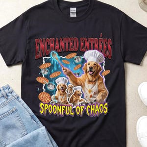 Può includere: Una t-shirt nera a maniche corte con una grafica di tre cani golden retriever che indossano cappelli da chef e grembiuli. Il testo recita ENCHANTED ENTREES e SPOONFUL OF CHAOS. I cani sono circondati da pizze e pentole fluttuanti.