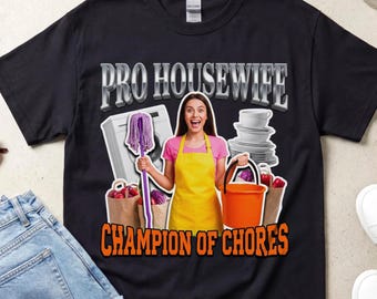 Pode incluir: Uma t-shirt preta com um gráfico de uma pessoa com avental amarelo segurando uma esfregona roxa e um balde laranja. O design inclui uma máquina de lavar, uma pilha de pratos, sacos de compras e o texto PRO HOUSEWIFE CHAMPION OF CHORES.
