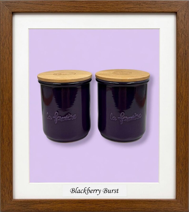 May include: Two deep purple ceramic canisters with light-colored wooden lids. Each canister features the embossed text "la fermi&egrave;re" on the front. The items are displayed within a brown wooden frame against a light purple background.