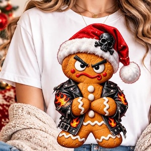 Puede incluir: Una camiseta blanca con el gráfico de un hombre de jengibre enfadado que lleva una chaqueta de cuero negra con llamas y un gorro de Papá Noel rojo con un emblema de calavera negra. La figura de jengibre tiene una superficie marrón.