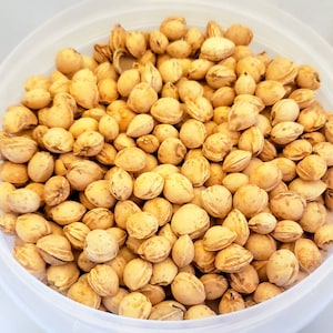 May include: A close-up of a bowl filled with light brown cherry pits.