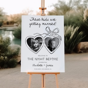 Op de afbeelding: Een wit bord op een houten ezel met de tekst "These kids are getting married!" en "Welcome to The Night Before" in zwart schrift. Twee hartvormige frames bevatten zwart-wit foto's van kinderen.