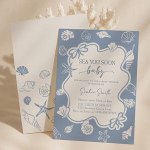 May include: Baby shower invitation with a blue and white seashell design. The invitation reads "Sea You Soon Baby" and includes event details. A matching envelope is also visible, featuring seashell illustrations.
