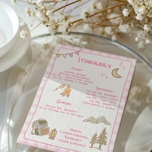 May include: A pink and white checkered itinerary card with hand-drawn illustrations of a campfire, backpack, mountains, and trees. The card lists daily activities, including camp games, pizza, and a farewell breakfast.