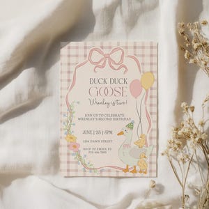May include: A pastel-colored birthday invitation with a duck and goose theme. The text reads "Duck Duck Goose, Wrenley is two!" and includes event details. The design features a plaid background, balloons, and floral accents.