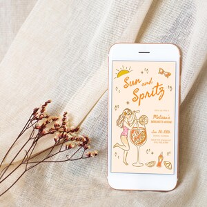 Puede incluir: Un tel&eacute;fono inteligente que muestra una invitaci&oacute;n digital para una fiesta con el tema "Sol y Spritz". La invitaci&oacute;n presenta una ilustraci&oacute;n de dibujos animados de una mujer sosteniendo un vaso de jugo de naranja con una pajita. El texto de la invitaci&oacute;n dice "Sol y Spritz" y "Fin de semana de despedida de soltera de Melissa".