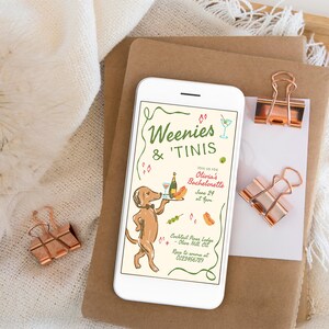 May include: A white smartphone displaying a bachelorette party invitation with the text Weenies & 'Tinis, featuring a brown dachshund wearing a bowtie and holding a tray with a bottle and glass, alongside illustrations of a hot dog and olives.