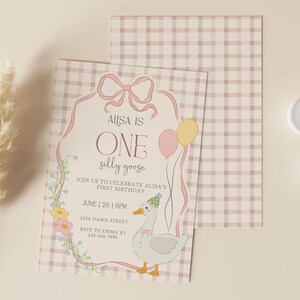 May include: A birthday invitation with a whimsical design. The invitation features a cartoon goose, balloons, and floral accents. The text reads "AUSA IS ONE silly goose" and includes event details. Two white candles and a decorative plant are also present.