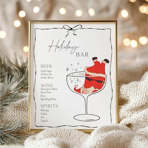 Peut inclure: Un panneau encadré avec une bordure dorée présente un design festif "Holiday BAR". L'illustration comprend une figure du Père Noël à l'intérieur d'un verre à vin. Le panneau répertorie la bière, le vin et les spiritueux.