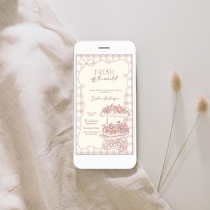 May include: A smartphone displays a floral-themed invitation with the text "Fresh off the market." The invitation features a cart filled with flowers and is set against a checkered background. Two dried flower stems are on the right.