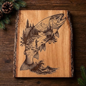 Op de afbeelding: Een rechthoekige houten plank met natuurlijke schorsranden voorzien van een lasergegraveerde illustratie van een springende vis. Het vissenlichaam bevat een gedetailleerde scène van een visser in een rivier tussen dennenbomen.