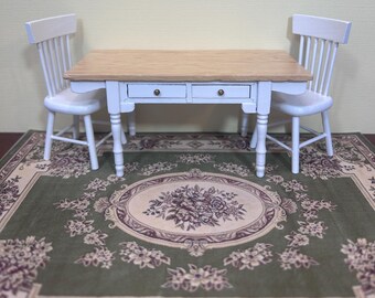 May include: A white wooden table with two white wooden chairs, set on a green floral patterned rug. The table has two drawers and a wooden top.