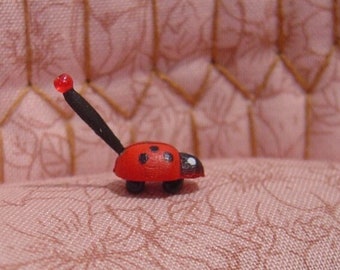 May include: A small red ladybug with black spots sits on a pink floral patterned couch. The couch has a tufted design and a white frame.