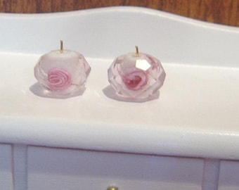 May include: Two clear glass candle holders with pink rose designs on a white dresser with six drawers.