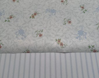 May include: A white wallpaper with a delicate floral pattern in shades of blue and pink. The bottom half of the image shows a white wallpaper with thin blue stripes.