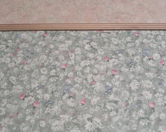 May include: A close-up of a light pink wall with a wood trim and a floral wallpaper with white and pink flowers on a green background.