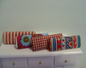 May include: Five fabric swatches in various patterns and colors. The swatches are red, white, blue, and brown. The patterns include stripes, gingham, and floral.