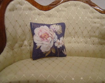 May include: A cream-coloured sofa with a floral cushion featuring a large pink rose and the word "France". The sofa has a diamond-patterned upholstery.