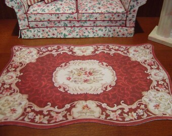 May include: A red and cream-colored area rug with a floral design. The rug has a scalloped edge and a central medallion with a floral pattern.