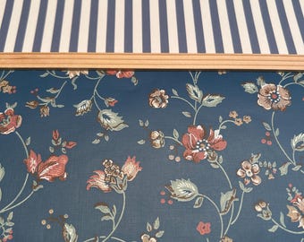 May include: Blue and white striped wallpaper with a floral pattern underneath. The floral pattern features small pink and brown flowers on a dark blue background.