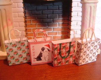 May include: Four miniature Christmas-themed gift bags with white rope handles. The bags feature festive patterns and images, including a puppy wearing a Santa hat and the text "HO HO HO". The bags are arranged in front of a fireplace.