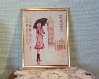 May include: A framed illustration of a woman walking in the rain in London. The woman is wearing a pink coat and holding an umbrella. The illustration includes Big Ben and other buildings in the background. The text "LONDON" is printed in the upper right corner of the illustration.