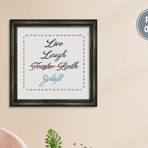 May include: A framed cross-stitch artwork with the words "Live Laugh Toaster Bath Zoloft" in black and blue script. The artwork is in a black frame and has a white background with a decorative border. A PDF ONLY sticker is in the upper right corner.