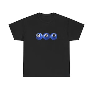 Peut inclure: T-shirt noir avec trois boules de billard bleues portant les lettres "D", "J" et "O". Les boules sont disposées horizontalement sur la poitrine.