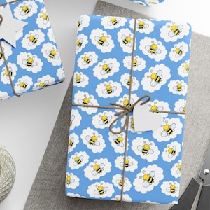May include: Gift-wrapped presents with blue wrapping paper featuring a pattern of yellow and black bees in white cloud shapes. The gifts are tied with twine and have a white heart-shaped tag.