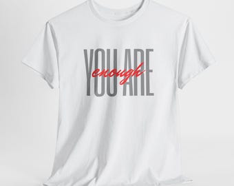 以下が含まれることがあります： グレーと赤で「YOU ARE enough」とプリントされた白いTシャツです。