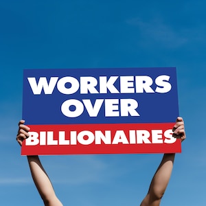 May include: A sign held aloft against a blue sky. The sign is split into two horizontal sections: a blue top with the words "WORKERS OVER" in white, and a red bottom with "BILLIONAIRES" in white.