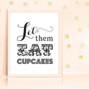 以下が含まれることがあります： 白い額縁に入ったプリントで、黒い文字で「Let them EAT CUPCAKES」と書かれています。背景は薄いピンクで、金色の水玉模様です。