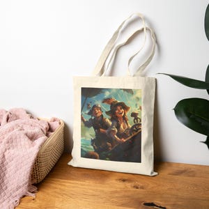 May include: A beige canvas tote bag featuring a colorful illustration of two cartoon pirates on a ship. The pirates are smiling and appear to be sailing on the ocean. The bag has a simple design with two handles.