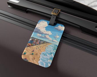 Op de afbeelding: Een rechthoekig bagagelabel met een strandscène met een blauwe lucht, witte wolken en oceaangolven. Het label is bevestigd aan een zwarte koffer met een bruine riem en een gouden gesp. Het strand heeft kleurrijke gebouwen en mensen.