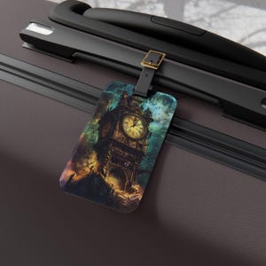 Könnte beinhalten: Ein rechteckiger Gepäckanhänger mit einer detaillierten Illustration eines gotischen Uhrturms. Das Kunstwerk hat ein Fantasy-Thema mit einem farbenfrohen Himmel und einer dunklen, mysteriösen Atmosphäre. Der Anhänger ist an einem schwarzen Gepäckgriff befestigt.