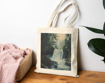 May include: A natural canvas tote bag featuring a scenic waterfall painting. The artwork depicts a cascading waterfall surrounded by lush green trees, creating a serene forest landscape. The bag has a light beige color and sturdy handles.