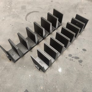 Puede incluir: Dos organizadores de plástico negro con múltiples ranuras para guardar objetos pequeños. Los organizadores están etiquetados como "T11" y "T12".