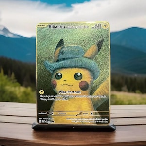 Op de afbeelding: Een goudkleurige Pikachu-kaart met Pikachu met een grijze hoed. De kaart heeft de tekst "Pikachu with Grey Felt Hat" en "Pika-Portrait". De achtergrond toont een bergketen.