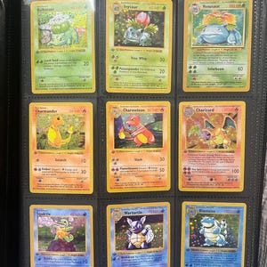 Può includere: Nove carte collezionabili Pokémon in un raccoglitore nero. Le carte presentano vari personaggi, tra cui Bulbasaur, Ivysaur, Venusaur, Charmander, Charmeleon, Charizard, Squirtle, Wartortle e Blastoise. Ogni carta ha un design e una combinazione di colori unici.