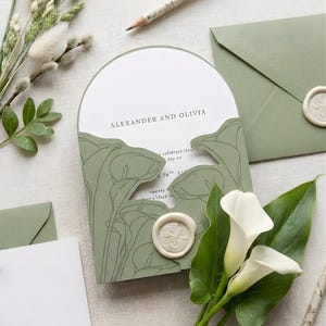 Può includere: Invito di nozze verde salvia con design floreale, con i nomi "Alexander e Olivia". Include un invito, una busta e un sigillo di cera. Sono presenti anche calle bianche e una matita con accenti floreali.