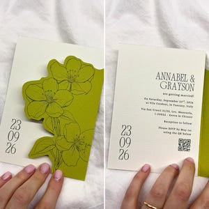 Könnte beinhalten: Hochzeitseinladung mit grünem Blumendesign und weißem Hintergrund. Die Einladung enthält das Datum, den 23. September 2026, und die Namen Annabel & Grayson. RSVP-Details sind mit einem QR-Code versehen.