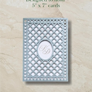 May include: A light blue laser-cut card holder with a lattice pattern and a central oval cutout featuring the monogram KD. The holder is designed to hold 5" x 7" cards. The intricate geometric design includes circular accents along the border.